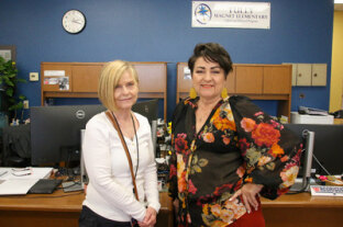 Susan Ramirez and Glenda Rodriguez smile in the front office of Tully Magnet Elementary School.